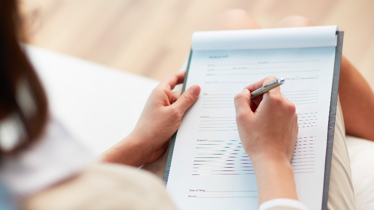 a woman writes on a clipboard | Dental Anxiety High Point NC